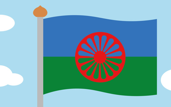 Romska flaggan på en flagstång, himmel och moln runt om.