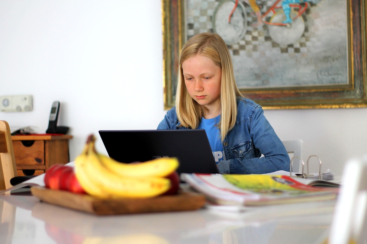 Flicka gör hemläxor på dator.
