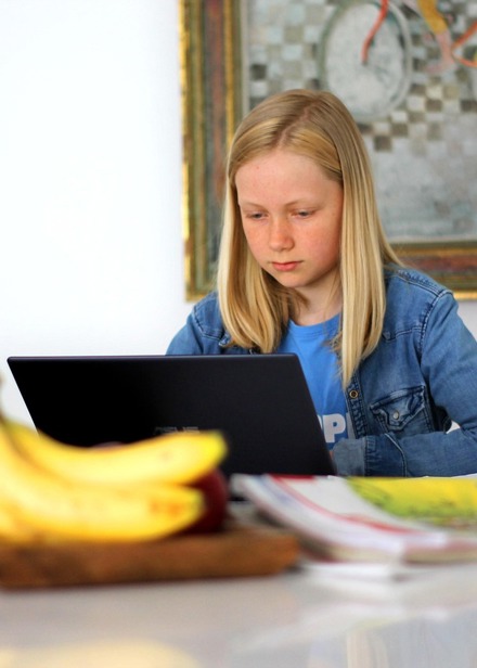 Flicka gör hemläxor på dator.