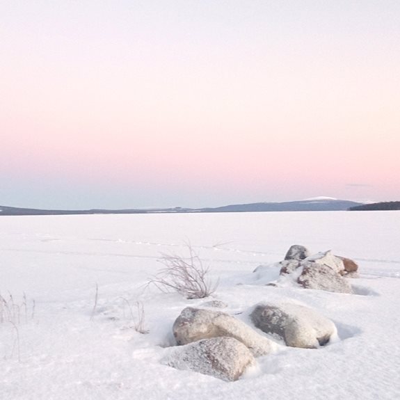 En snötäckt sjö med berg i bakgrunden.