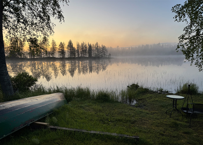 Utsikt över en sjö. Till vänster en båt som ligger upp och ned på land.