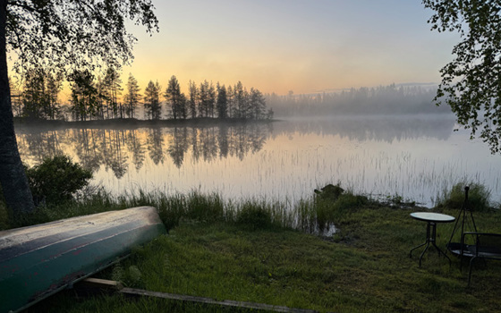 Utsikt över en sjö. Till vänster en båt som ligger upp och ned på land.