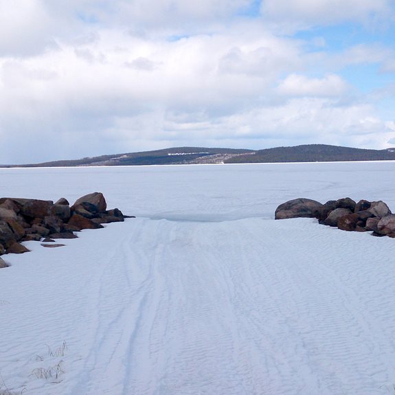 En snötäckt sjö med berg i bakgrunden.