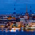 Foto över en stad på kvällen, kyrkan och en stor båt syn tydligt på bilden.