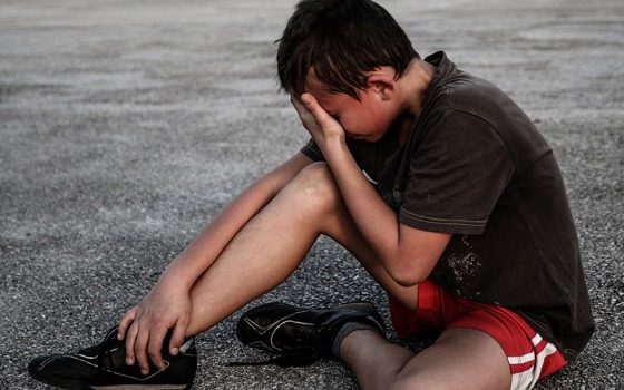 Barn som sitter på gruset och är ledsen. 