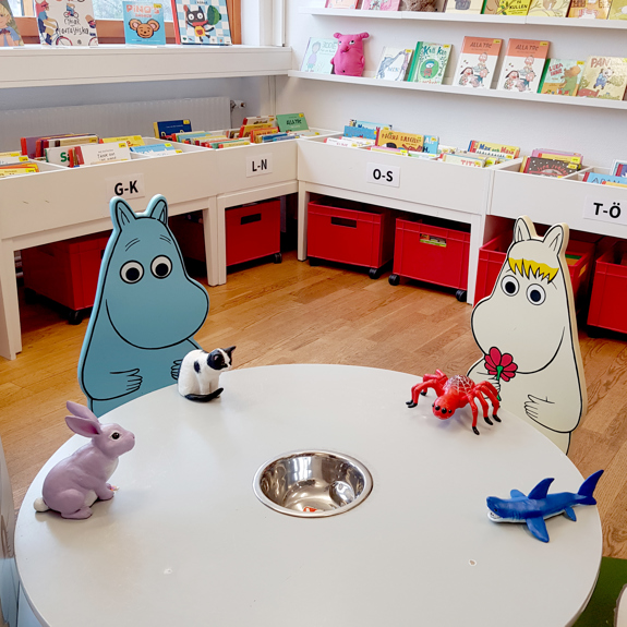 Kaninen, Katten, Spindeln och Hajen sitter vid ett bord på biblioteket.