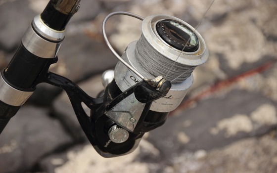 Närbild på ett fiskespö med rulle.