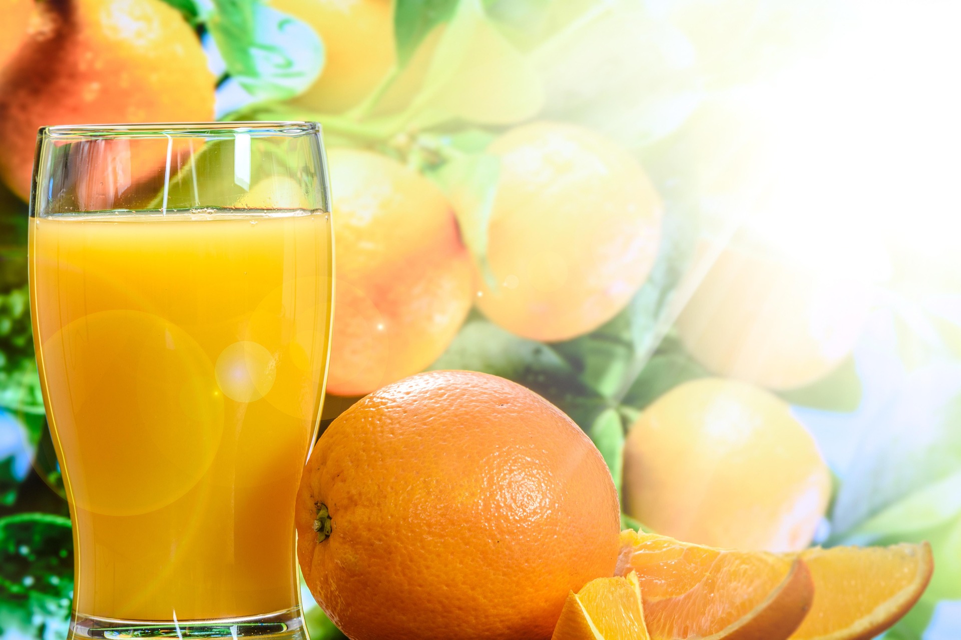 Apelsinjuice i ett glas och apelsiner runt om.