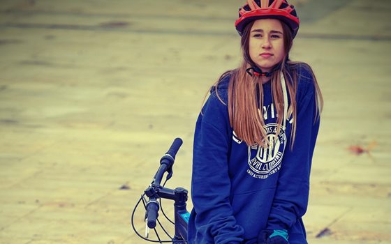 Tjej som sitter bak och fram på sin cykel.