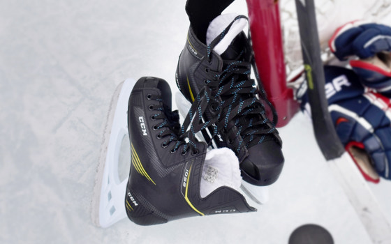 Skridskor, klubba och hockyhandskar som ligger på isen.