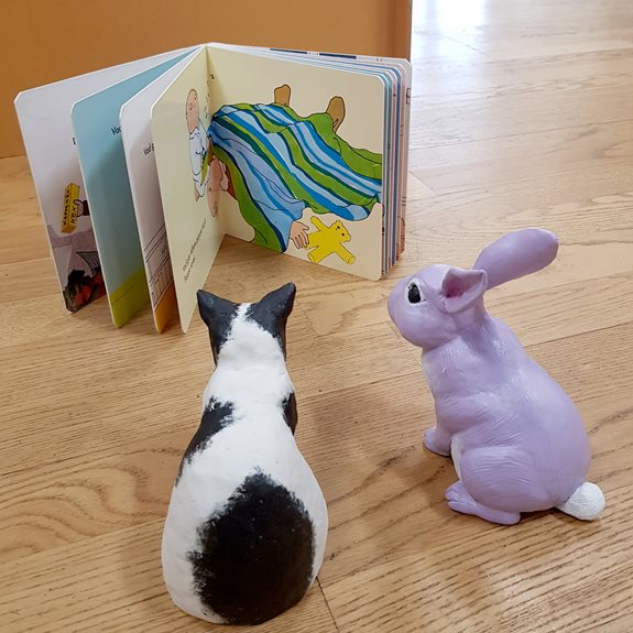 Katten och kaninen läser en bok tillsammans.