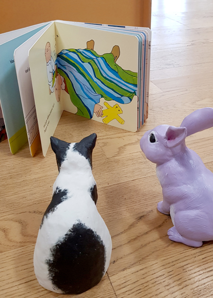 Katten och kaninen läser en bok tillsammans.