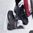 Skridskor och klubba som ligger på isen.