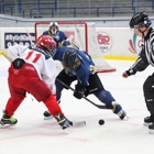 Två hockeyspelare och en domare ute på hockeplanen.